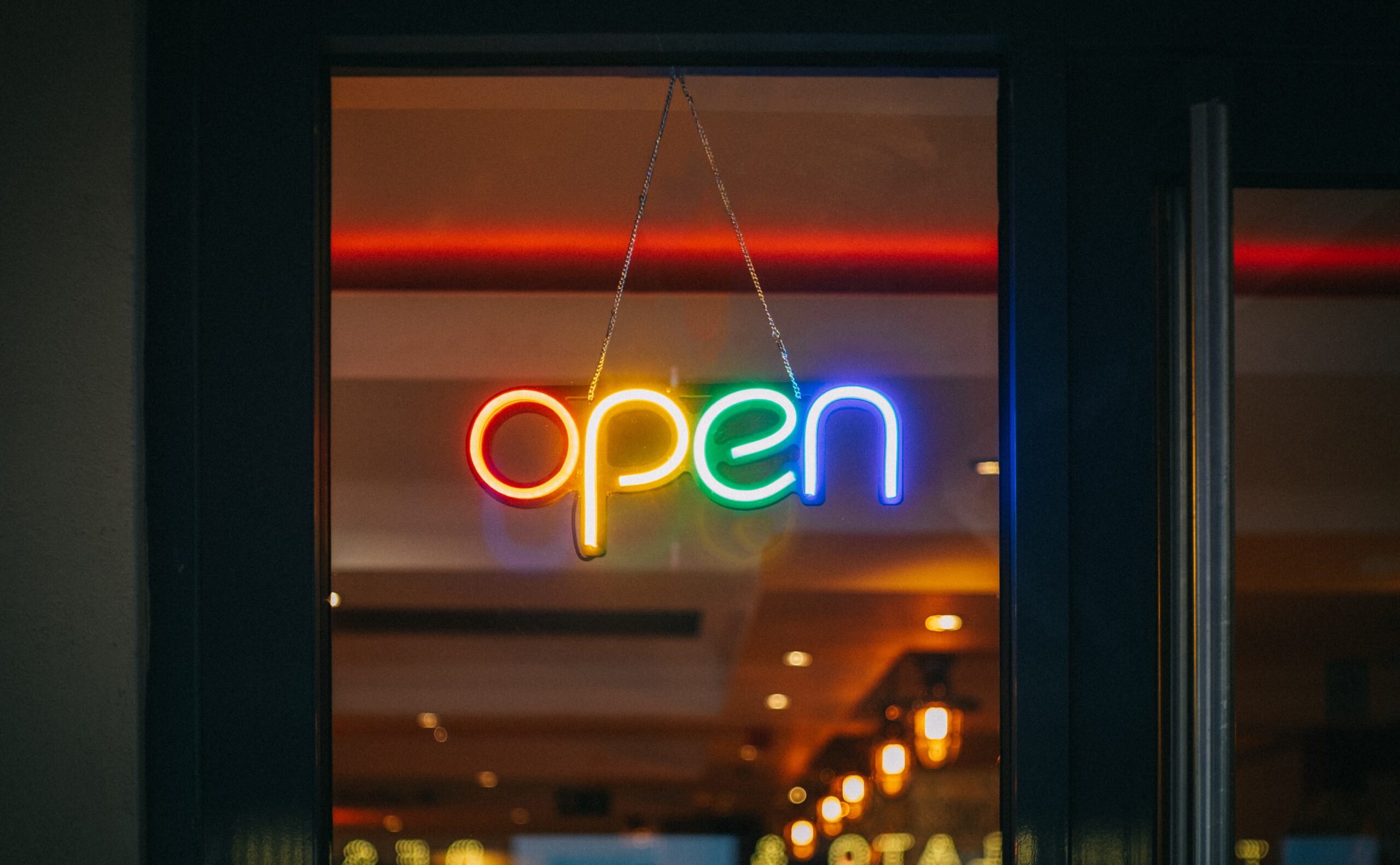 Neon "open" sign hanging in a door.